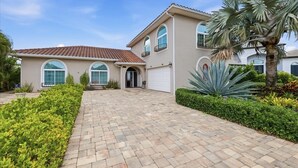 A two-story house with a tiled roof, large arched windows, and a paved driveway. - Luxury Riverfront Retreat with Pool & Hot Tub (Cape Coral)