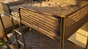 A bunk bed with a grey quilted mattress, metal frame, and a small stuffed toy on the top bunk. - Ideal accommodation for families 5 min from Tourcoing ouigo station (Tourcoing)