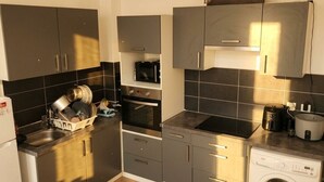 A modern kitchen with grey cabinets, a microwave, an oven, a sink, and a washing machine. - Ideal accommodation for families 5 min from Tourcoing ouigo station (Tourcoing)