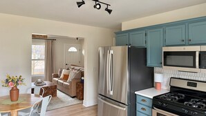Una cocina moderna con electrodomésticos de acero inoxidable, armarios color turquesa y un comedor con mesa y sillas de madera.