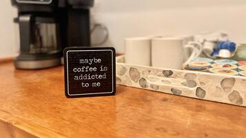 A coffee maker, a coffee pod holder, and a sign with a coffee-related message.