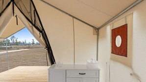A tented area with a wooden deck, a white cabinet with drawers, and a red flag on the wall.