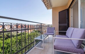 Ein Balkon mit Metallgeländer, zwei Stühlen, einem kleinen Tisch und einer Schiebetür.