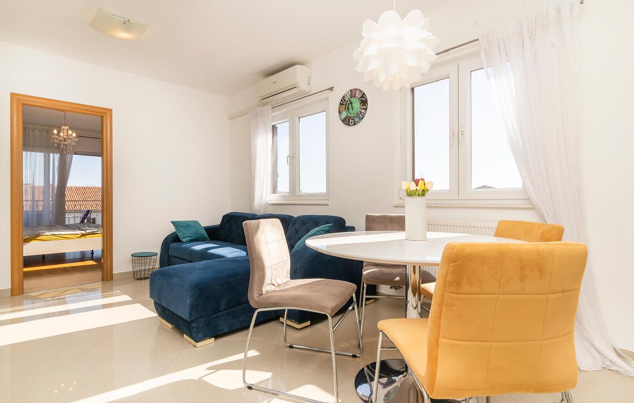 Una sala moderna con un sofá azul, una mesa redonda y una silla amarilla.