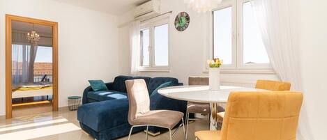 Una sala moderna con un sofá azul, una mesa redonda y una silla amarilla.
