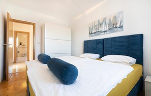 Ein Hotelzimmer mit Bett, einem Bild, einem Kleiderschrank und einem durch eine offene Tür einsehbaren Badezimmer.