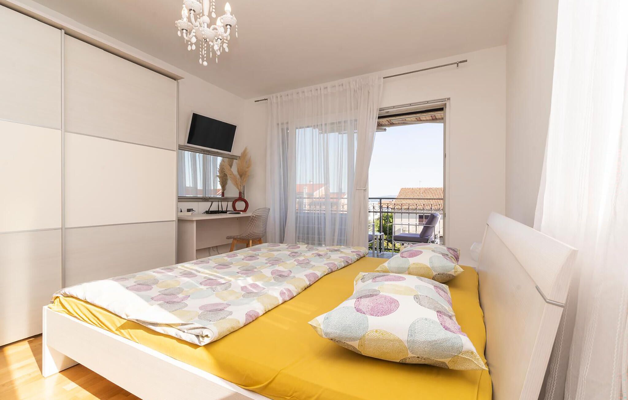 Een slaapkamer met een bed, een bureau, een televisie en een raam met uitzicht.