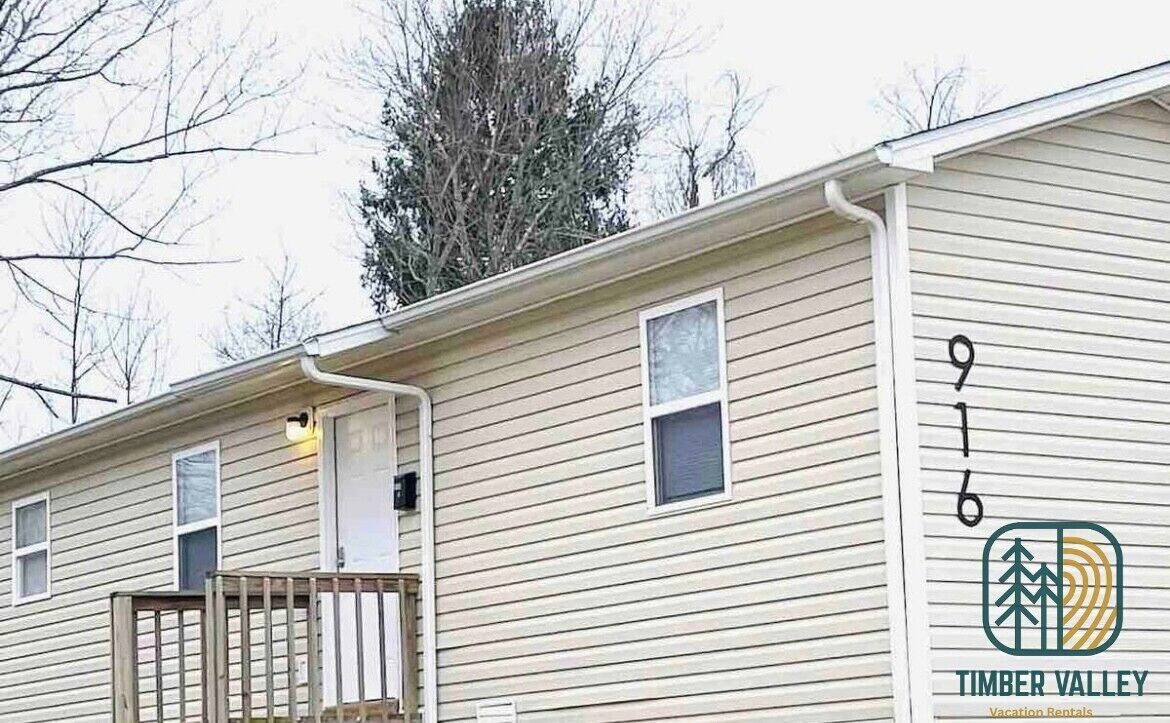 A single-story building with a number '916' on the side, a small porch, and a logo for 'Timber Valley Vacation Rentals'.