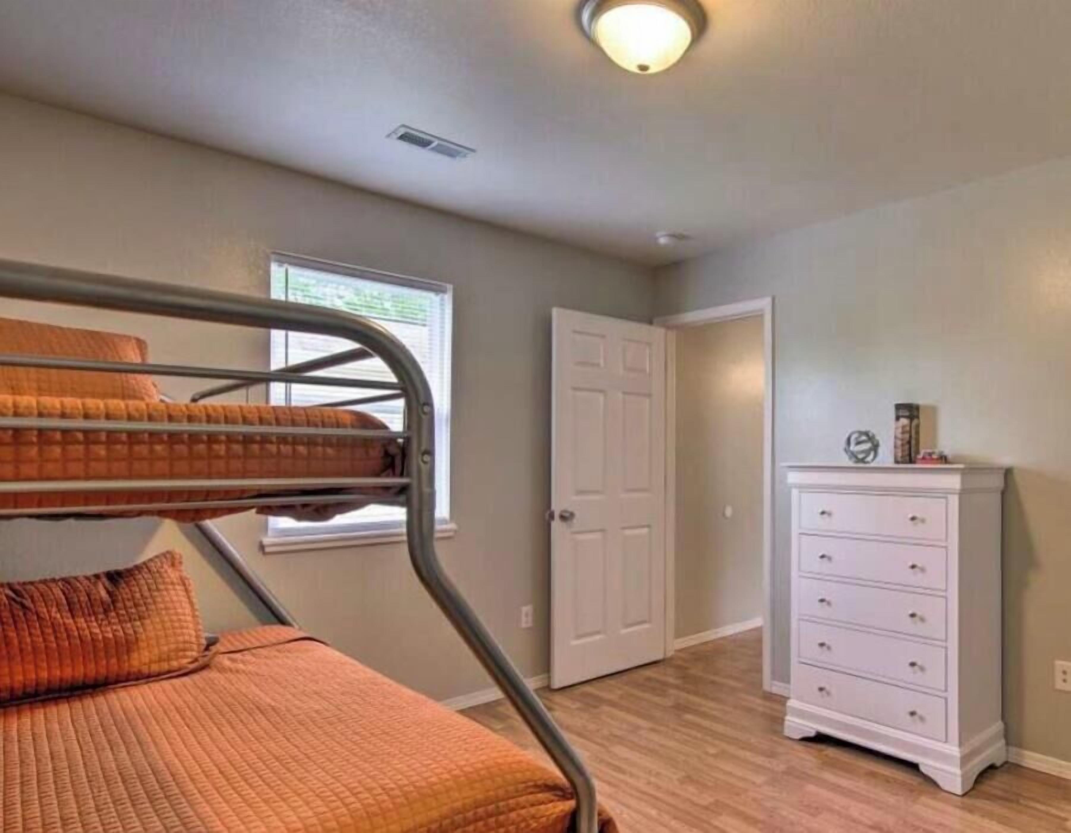 Una habitació amb lliteres, un taulell blanc, una porta i una finestra.