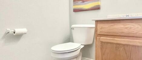 Un baño con inodoro, un armario de madera y un cuadro en la pared.