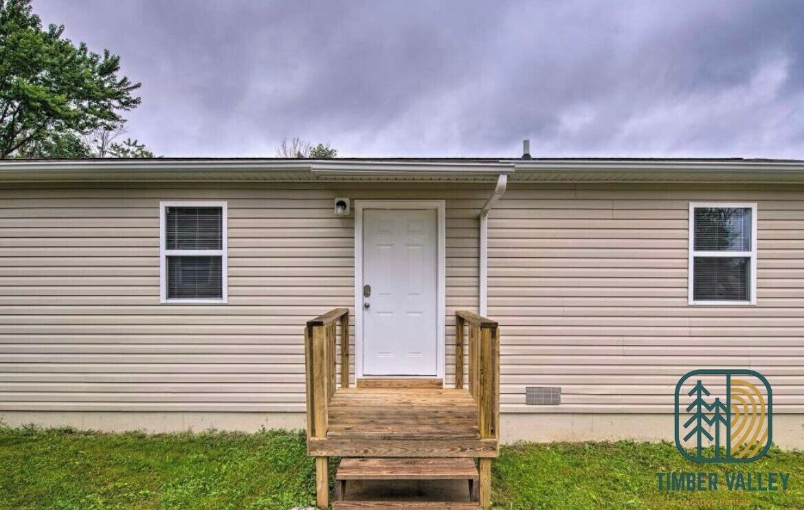 Une maison mobile de plain-pied, dotée d’un porche à l’avant, d’une porte blanche et de deux fenêtres.
