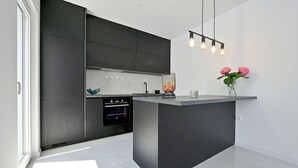 A modern kitchen with a central island, built-in oven, and pendant lighting. - Cozy home in Donji Prolozac (Donji Prolozac)