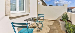 A balcony with a table and chairs, a window, and potted plants. - Cozy Beach Studio – Walk to Ocean, Market & Cafés (Saint-Hilaire-de-Riez)