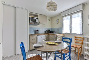 A compact kitchen with a microwave, coffee maker, and a dining table with chairs. - Cozy Beach Studio – Walk to Ocean, Market & Cafés (Saint-Hilaire-de-Riez)