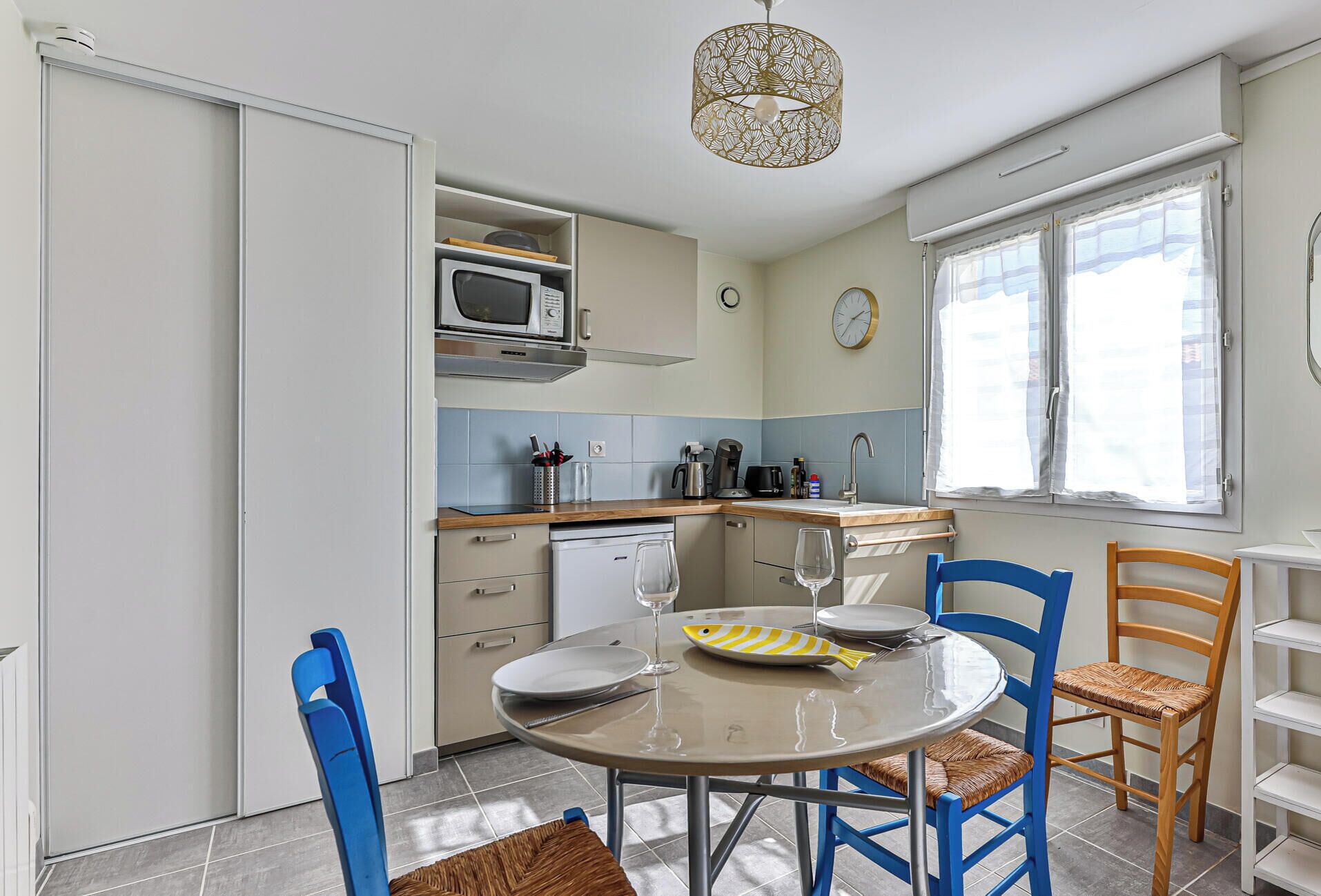A compact kitchen with a microwave, coffee maker, and a dining table with chairs.