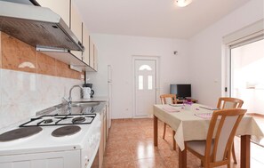 A kitchen with a stove, sink, and a dining area with a table and chairs. - Gorgeous apartment in Rogoznica with WiFi (Rogoznica)