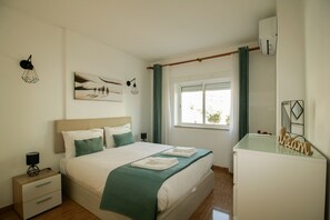 A bedroom with a bed, bedside tables, a dresser, a window with curtains, and wall art. - FLH Armação Pêra Beachside Bliss (Armação de Pêra)