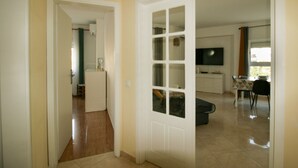 An open door leading to a living area with a dining table, chairs, and a television. - FLH Armação Pêra Beachside Bliss (Armação de Pêra)