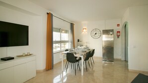 A modern kitchen with a dining area, a flat-screen TV, and a stainless steel refrigerator. - FLH Armação Pêra Beachside Bliss (Armação de Pêra)
