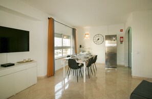 A modern kitchen with a dining area, a flat-screen TV, and a stainless steel refrigerator. - FLH Armação Pêra Beachside Bliss (Armação de Pêra)