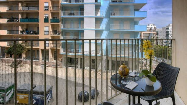 A balcony with a round table, chairs, and a potted plant. - FLH Armação Pêra Beachside Bliss (Armação de Pêra)