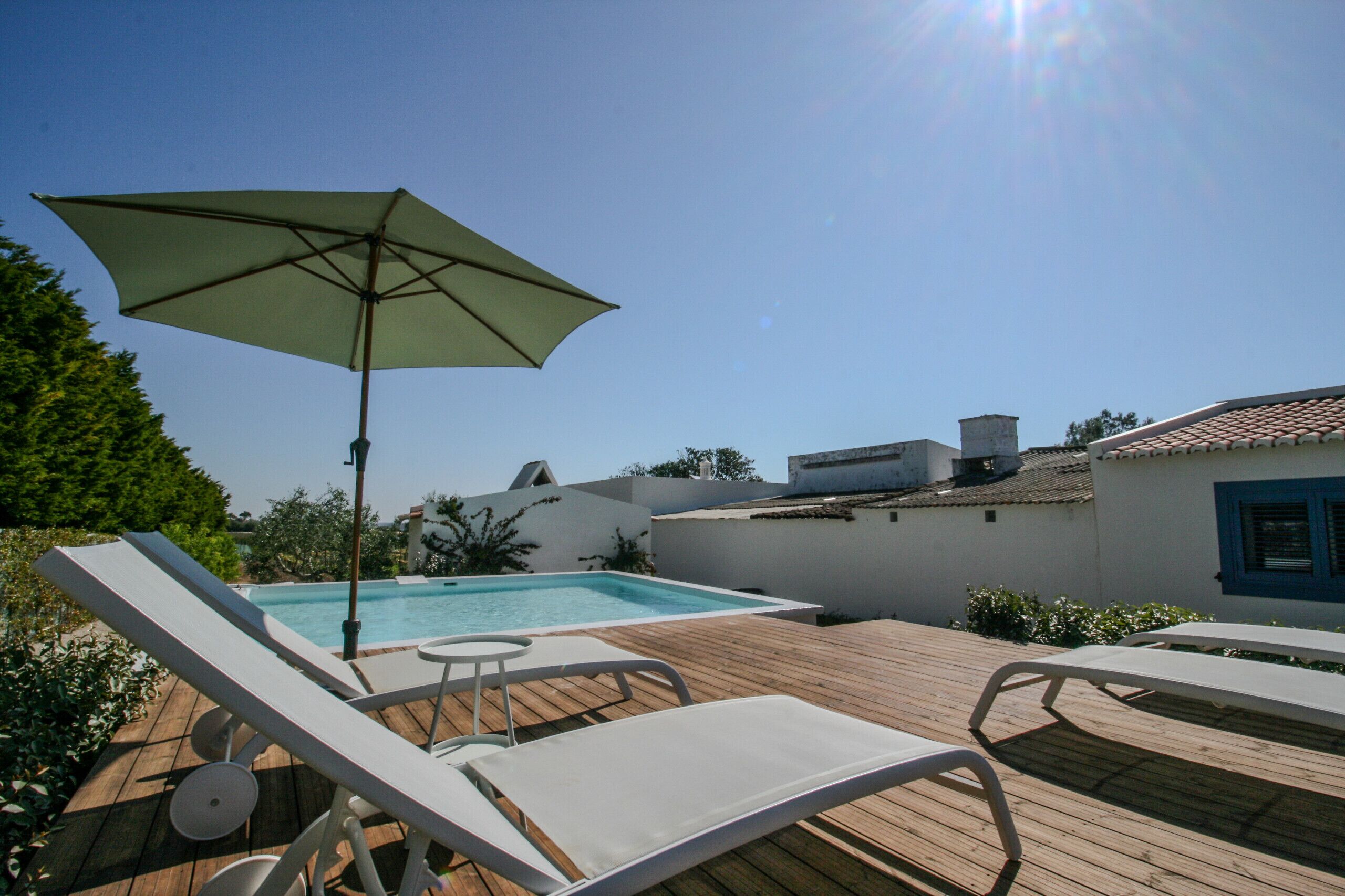 A rooftop pool area with lounge chairs and an umbrella.