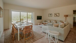 A spacious living room with a dining area, a sofa set, and a flat-screen TV mounted on the wall. - FLH Luz Tavira Al-Lagar I (Tavira)