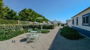 A gravel pathway leading to a seating area with chairs and a table, surrounded by greenery and a building with shutters. - FLH Luz Tavira Al-Lagar I (Tavira)