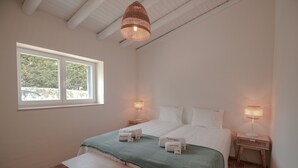 A bedroom with a bed, bedside tables, a bench, a window, and a hanging light fixture. - FLH Luz Tavira Al-Lagar II (Tavira)