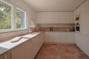 Eine Küche mit weißen Schränken, einem Fenster, einer Spüle und einer Mikrowelle.