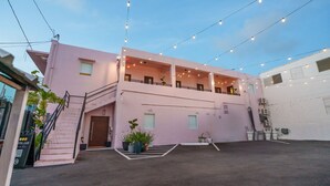 A pink building with a staircase, balconies, and string lights. - San Juan Group Stay | 16 Rooms | Sleeps 32| Parking (San Juan)
