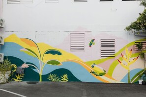 Ein Gebäude mit einem farbenfrohen Wandgemälde, das abstrakte Pflanzen- und Tiermotive zeigt.