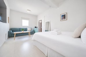 A modern hotel room with a large bed, a sofa, a small table, and a microwave. - San Juan Group Stay | 16 Rooms | Sleeps 32| Parking (San Juan)