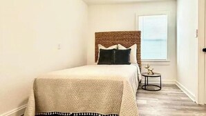 A bedroom with a bed, a ceiling fan, a window with a view, and a small table with a decorative item. - Cozy 1BR Entire Unit in W. Plains, nice location! (West Plains)