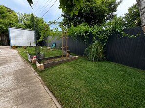 A backyard with a raised garden bed, a wooden trellis, and a black fence. - Punkin’s House • Sleeps 8 • Pet-Friendly Near Hard Rock Stadium (Miami)