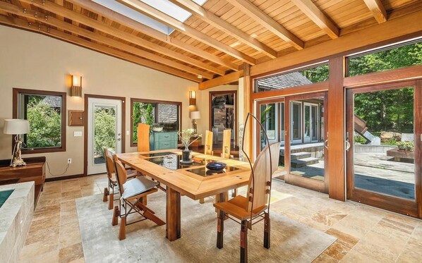 Un comedor amplio con una mesa y sillas de madera, ventanas grandes y vistas al exterior.