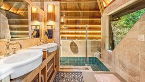 Een moderne badkamer met houten balken, een douchecabine van glas en uitzicht op groen.