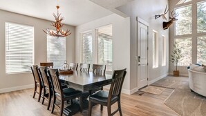 A dining area with a large table, chairs, and a chandelier.