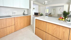 Una cocina moderna con armarios de madera, encimera blanca y un frutero.