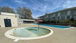 A swimming pool with a circular design, surrounded by a paved area, and adjacent buildings. - Air-conditioned house in the Arcachon style with swimming pool (La Teste-de-Buch)