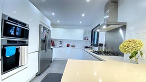 Una cucina moderna con mobili bianchi, elettrodomestici in acciaio inossidabile, un'isola centrale e un vaso con fiori.