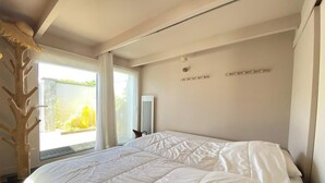 Un dormitorio con una cama grande, una ventana con cortinas y una escultura de árbol de madera.