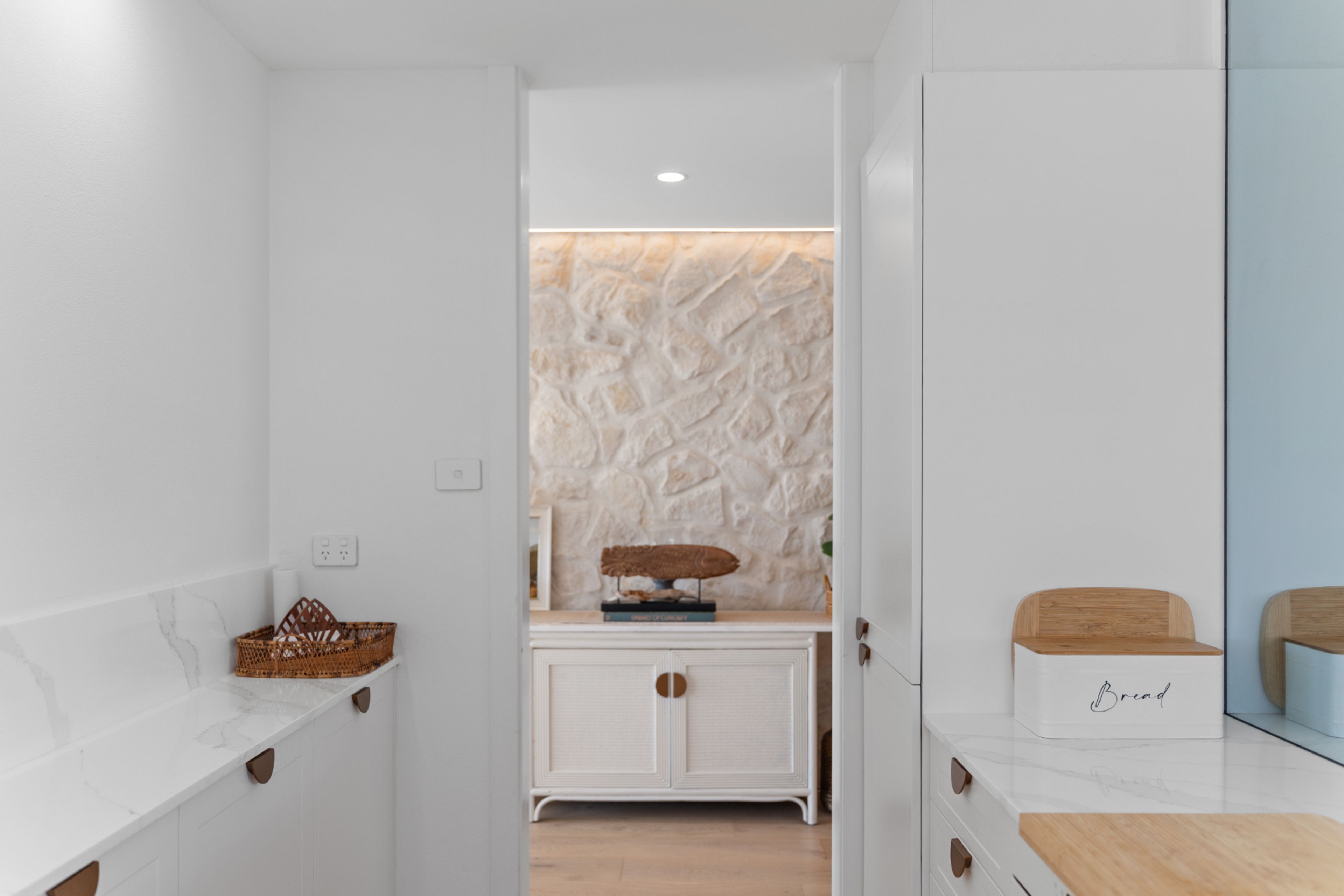 A modern kitchen with white cabinetry, a marble countertop, and a stone backsplash.