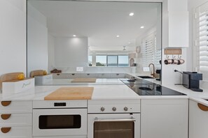 Eine moderne Küche mit einer großen Kochinsel, Backofen und Meerblick durch die Fenster.