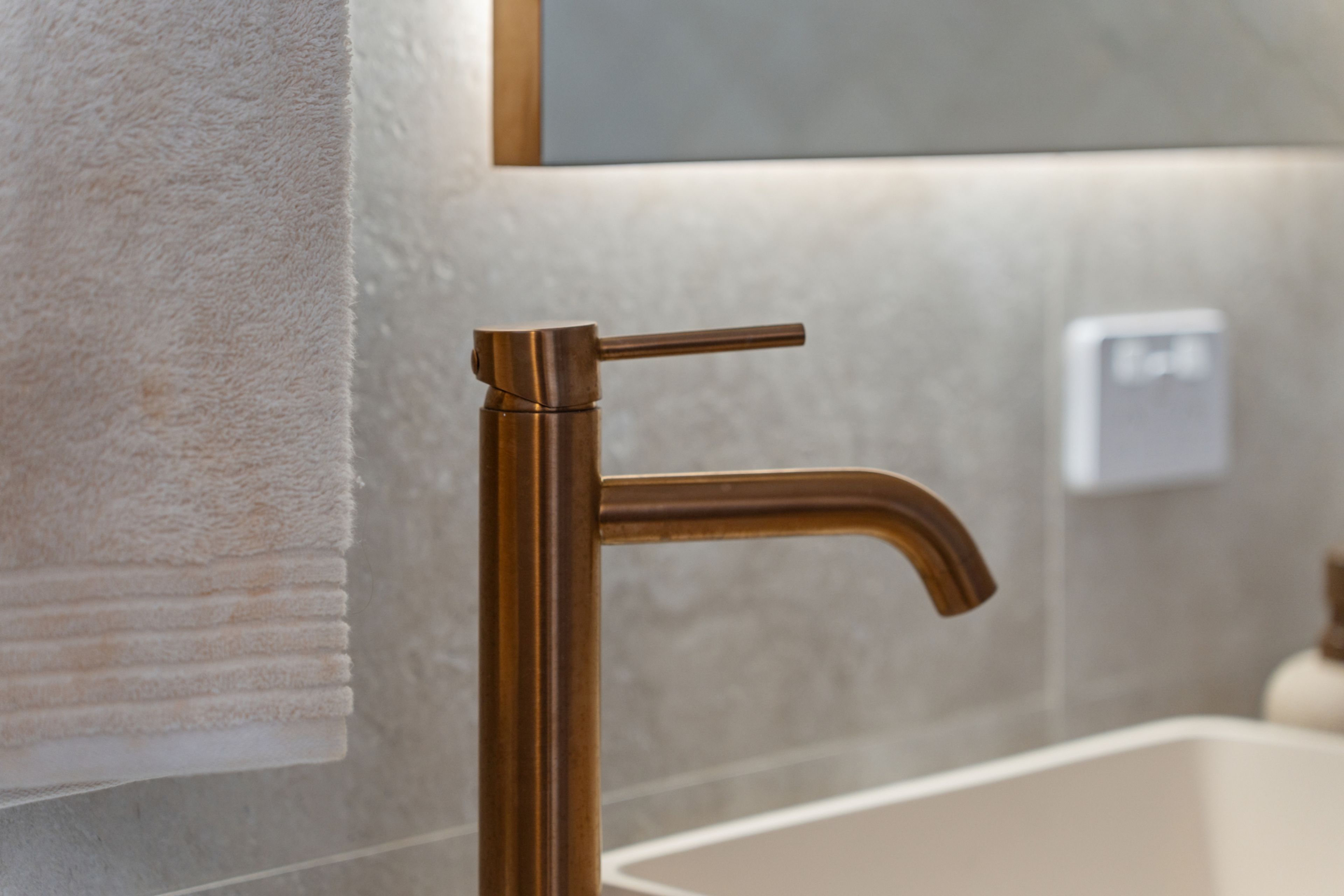 Une salle de bain dotée d’un robinet moderne, d’un porte-serviettes et d’un interrupteur fixé au mur.