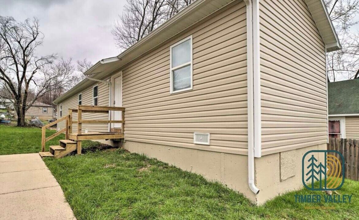 A single-story house with a front porch, a visible window, and a small step leading to the entrance.