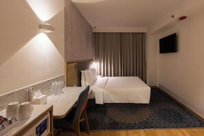 A hotel room with a bed, a desk with a chair, a TV on the wall, and a window with curtains. - Holiday Inn Express Greater Noida Knowledge Park (Greater Noida)