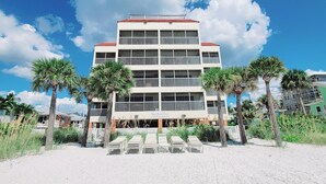 Un hôtel à plusieurs étages, doté d’un toit rouge, de balcons et situé en bord de mer.