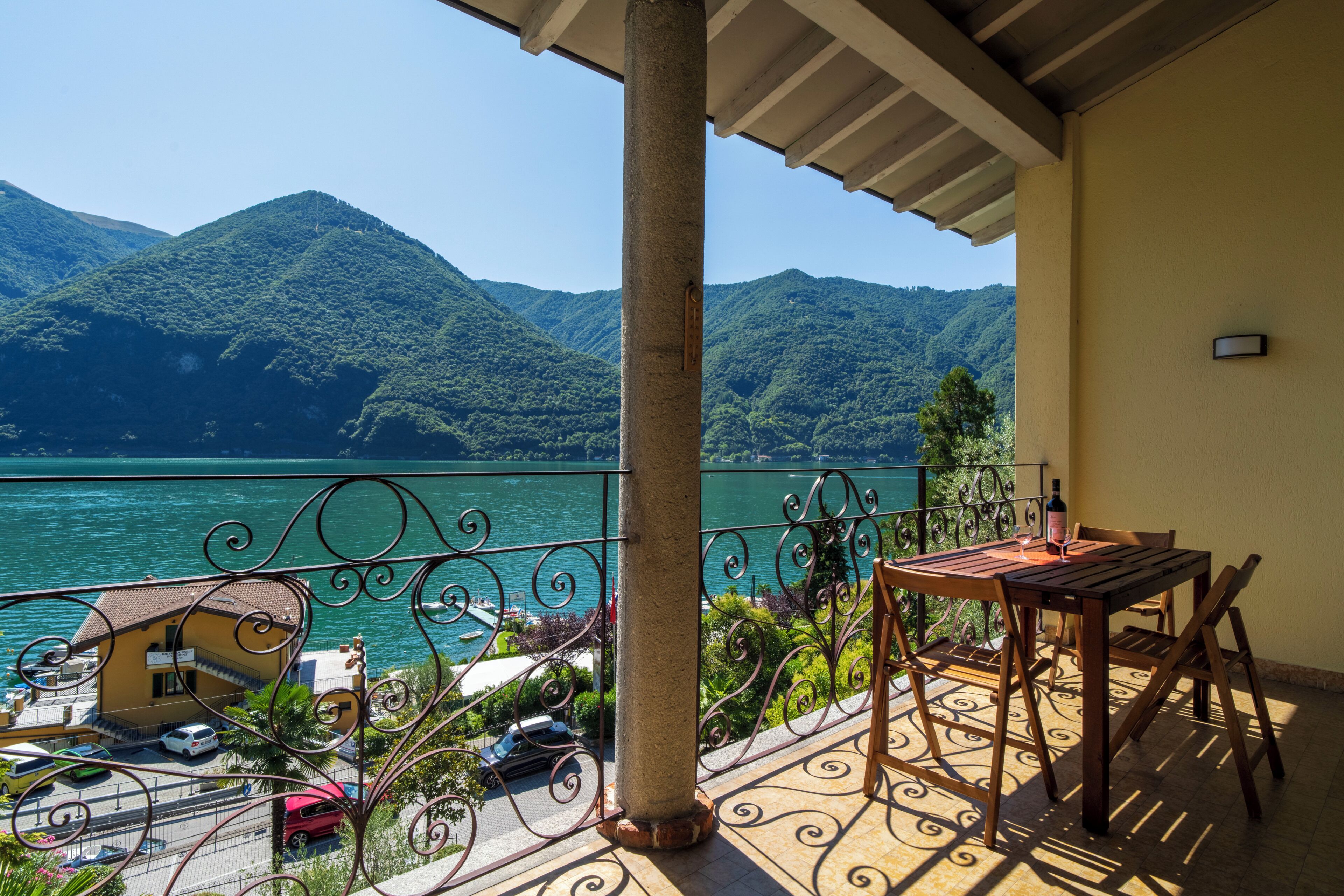 Ein Balkon mit Tisch und Stühlen, mit Blick auf einen See und Berge.