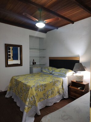 Une chambre à coucher avec un lit, une table de chevet, une lampe et un ventilateur de plafond.